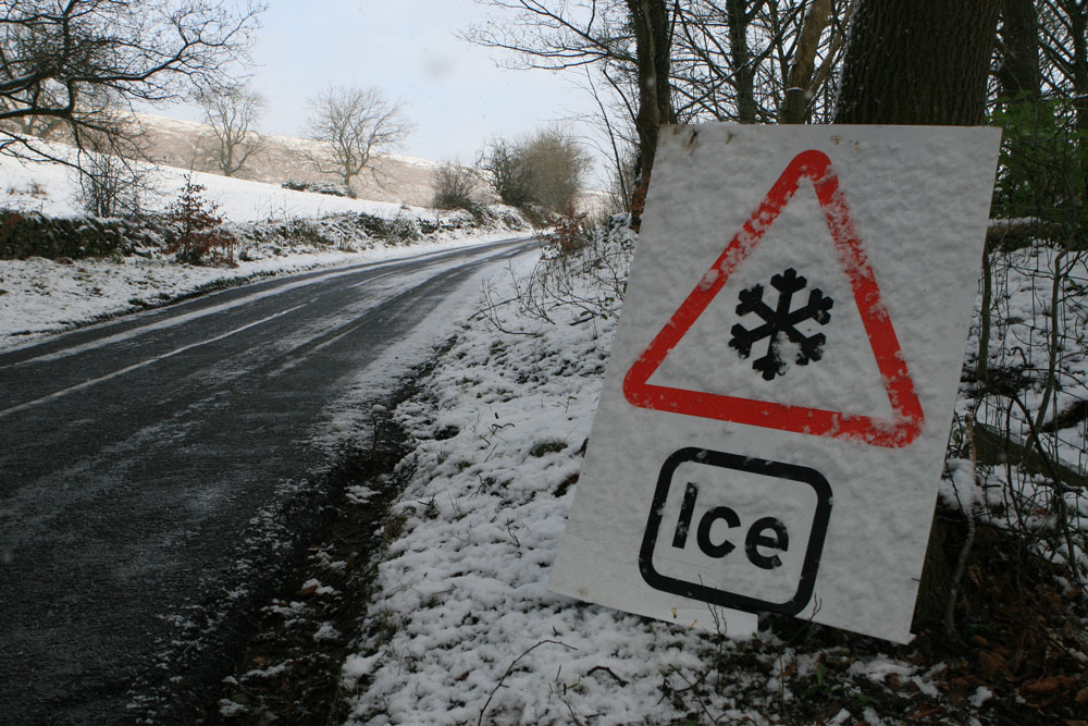 Icy road sign on the side of an icy road